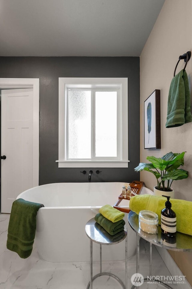 bathroom featuring a soaking tub and marble finish flooring