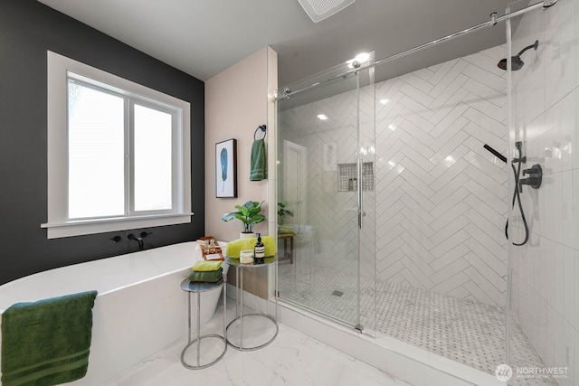 bathroom with a stall shower, a soaking tub, and marble finish flooring