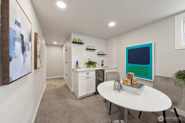 kitchen featuring a sink, open shelves, light countertops, light colored carpet, and recessed lighting