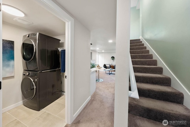 laundry room featuring stacked washer and clothes dryer, baseboards, tile patterned floors, and recessed lighting