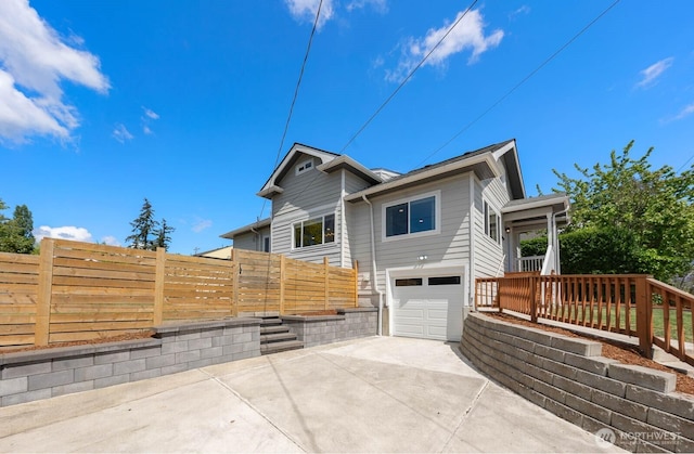 view of side of home with driveway, fence, and an attached garage