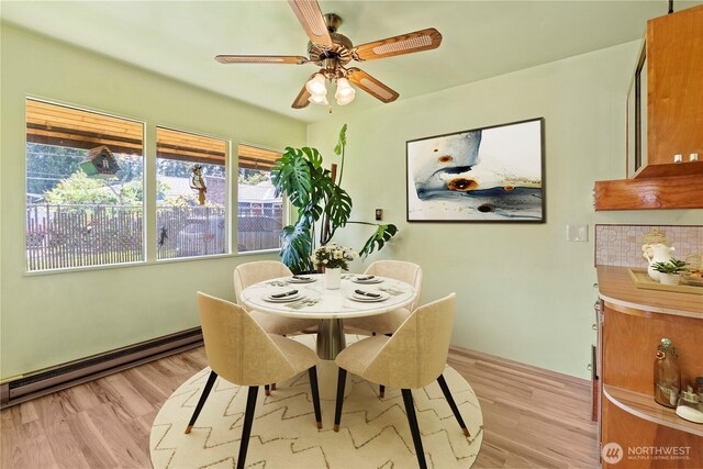 dining space with a baseboard radiator, light wood-style flooring, and a ceiling fan