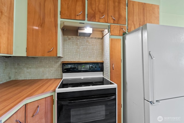 kitchen featuring black / electric stove, freestanding refrigerator, under cabinet range hood, light countertops, and backsplash