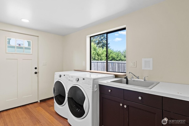 laundry area featuring washer and dryer, cabinet space, and light wood-type flooring