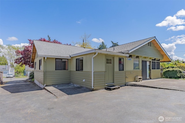 view of front of home with roof with shingles and a patio area