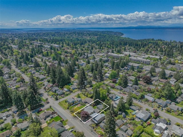 aerial view of residential area featuring property parcel outlined, a forest, and a nearby body of water