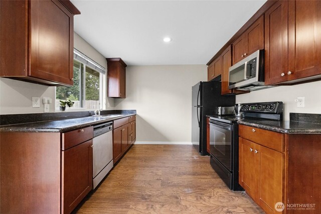 kitchen featuring stainless steel appliances, light wood-type flooring, baseboards, a sink, and recessed lighting