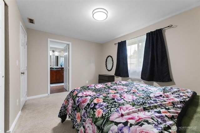 carpeted bedroom featuring baseboards and connected bathroom