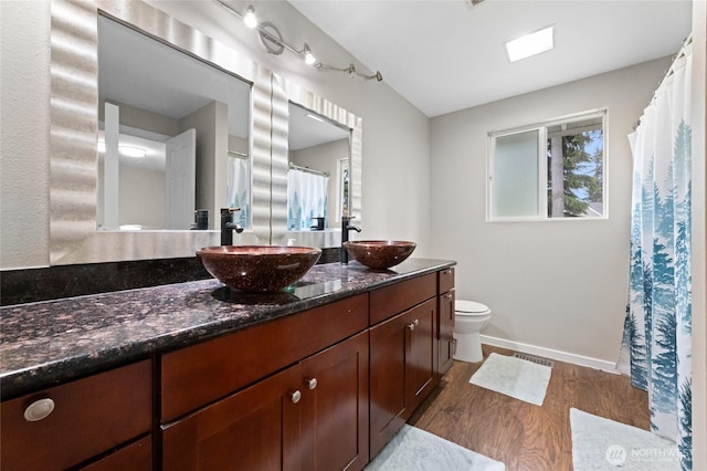 full bath with wood finished floors, double vanity, toilet, baseboards, and curtained shower