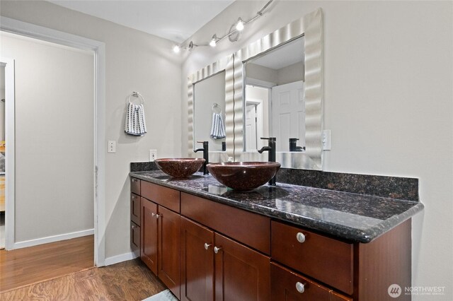 bathroom with wood finished floors, double vanity, and baseboards