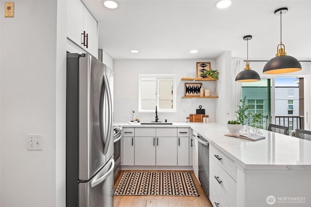 323 Queen Anne Ave N Unit 502, Seattle, WA 98109 - kitchen with appliances with stainless steel finishes, a sink, a peninsula, light wood-style floors, and recessed lighting