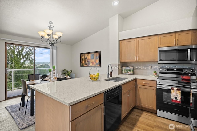 kitchen featuring stainless steel appliances, a sink, lofted ceiling, a peninsula, and a chandelier