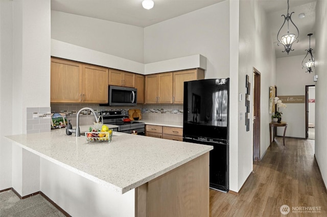 kitchen featuring stainless steel appliances, a peninsula, decorative backsplash, brown cabinets, and light wood-style floors