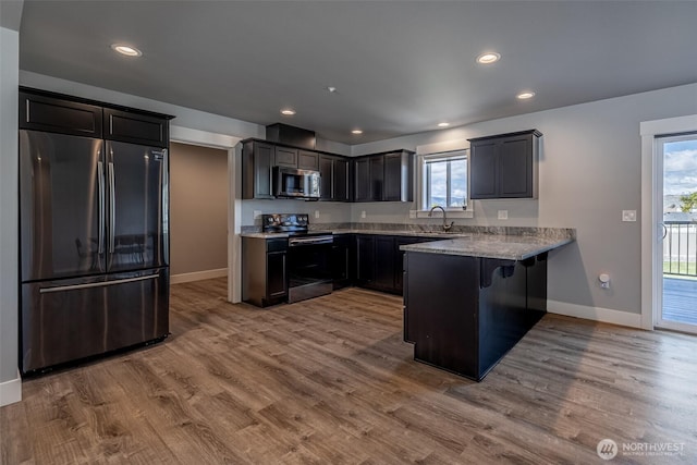 2436 Berkley Loop, East Wenatchee, WA 98802 - kitchen featuring appliances with stainless steel finishes, a peninsula, baseboards, wood finished floors, and healthy amount of natural light