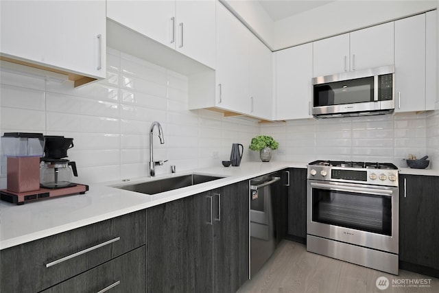 109 22nd Ave E Unit C, Seattle, WA 98112 - kitchen featuring appliances with stainless steel finishes, a sink, white cabinets, and decorative backsplash