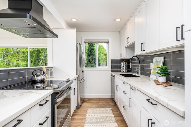 6533 106th Ave NE Unit D, Kirkland, WA 98033 - kitchen featuring appliances with stainless steel finishes, wall chimney range hood, a sink, baseboards, and white cabinetry