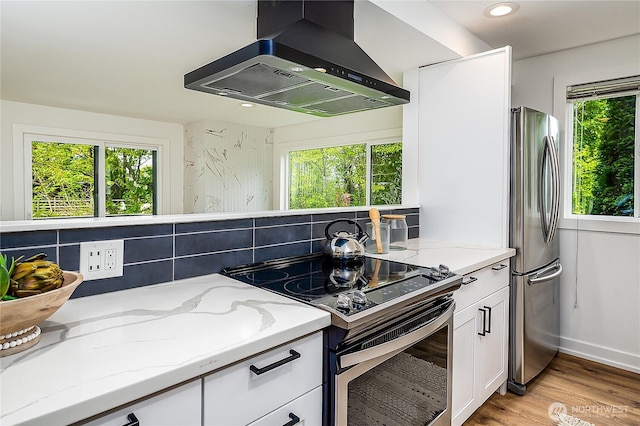 6533 106th Ave NE Unit D, Kirkland, WA 98033 - kitchen with ventilation hood, stainless steel appliances, white cabinetry, light stone countertops, and light wood-style flooring