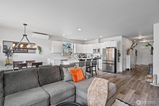 817 B St, Vader, WA 98593 - living room with dark wood-type flooring, a wall mounted air conditioner, a chandelier, recessed lighting, and a textured ceiling