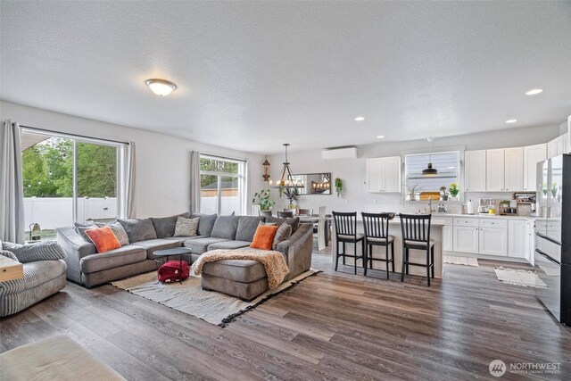 817 B St, Vader, WA 98593 - living area featuring a wall mounted air conditioner, dark wood finished floors, a chandelier, recessed lighting, and a textured ceiling
