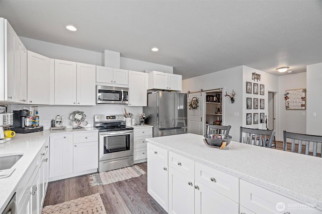 817 B St, Vader, WA 98593 - kitchen with appliances with stainless steel finishes, dark wood-type flooring, white cabinetry, light stone countertops, and recessed lighting