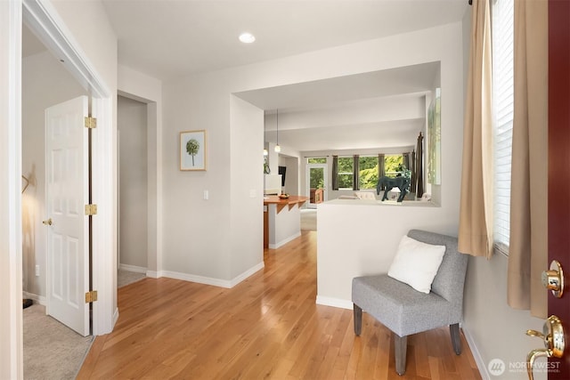 corridor with light wood-style flooring, baseboards, and recessed lighting