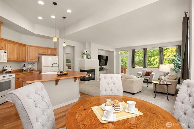 dining room with a glass covered fireplace, recessed lighting, and light wood-style floors