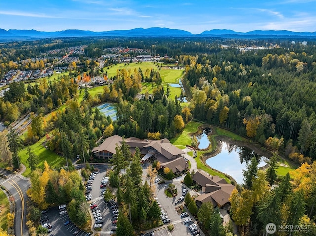 aerial view of property and surrounding area with a water and mountain view and a forest