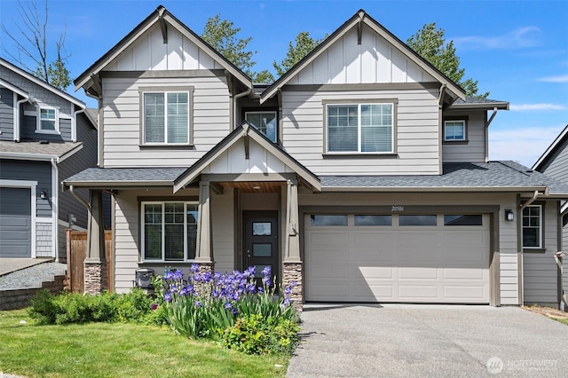 craftsman inspired home featuring board and batten siding, asphalt driveway, an attached garage, and a shingled roof