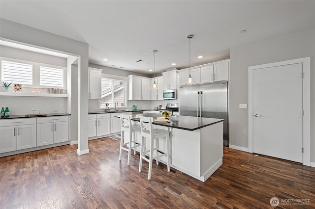 kitchen featuring stainless steel appliances, dark countertops, dark wood-style floors, white cabinetry, and recessed lighting
