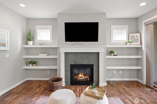 living area featuring wood finished floors, a tiled fireplace, healthy amount of natural light, and recessed lighting