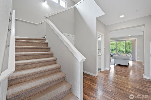 staircase with wood finished floors, baseboards, and recessed lighting