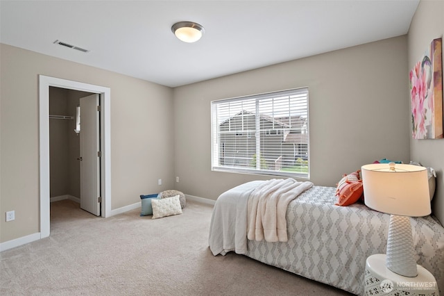 bedroom with carpet, a walk in closet, and baseboards