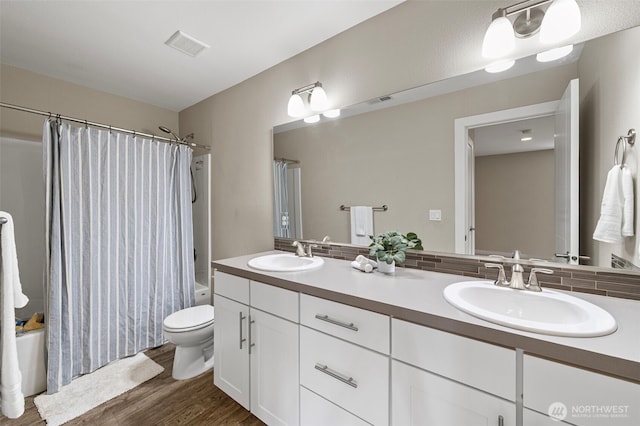 full bathroom with shower / bath combo with shower curtain, wood finished floors, double vanity, toilet, and tasteful backsplash