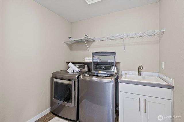 clothes washing area featuring washing machine and dryer, cabinet space, baseboards, and wood finished floors