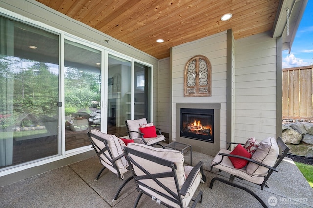view of patio featuring a glass covered fireplace and fence