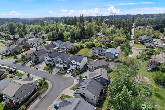 view of property location featuring nearby suburban area and a heavily wooded area