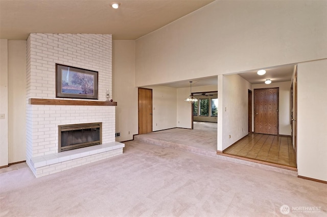 2526 E Pershing Ct, Shelton, WA 98584 - unfurnished living room with carpet, a fireplace, a towering ceiling, a chandelier, and baseboards