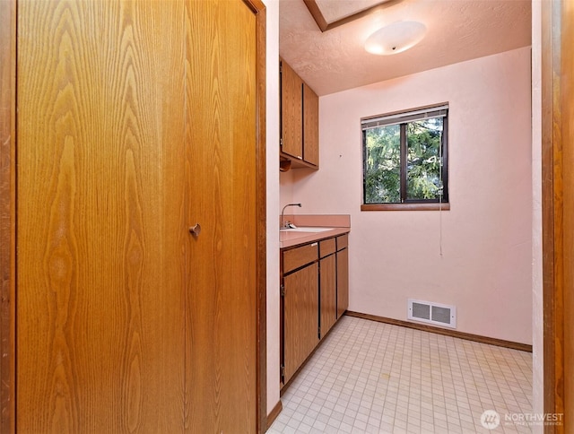 2526 E Pershing Ct, Shelton, WA 98584 - laundry area featuring baseboards, a sink, and light tile patterned flooring