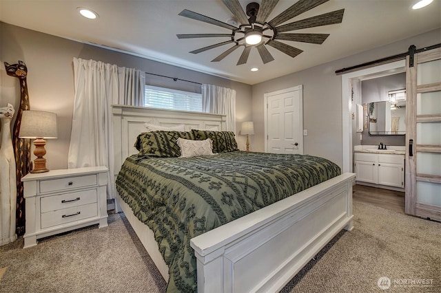 bedroom with a barn door, recessed lighting, and connected bathroom