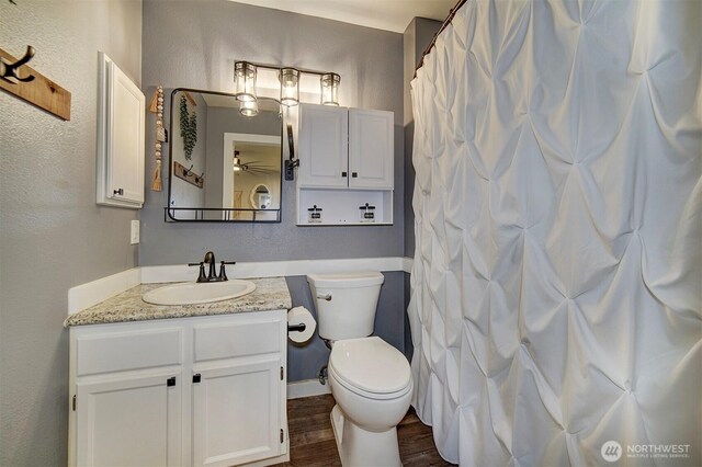 full bathroom featuring a textured wall, ceiling fan, vanity, toilet, and wood finished floors
