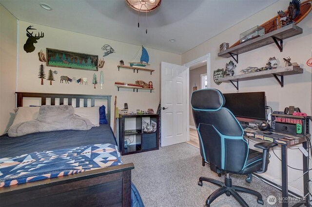 carpeted bedroom with an office area and a ceiling fan