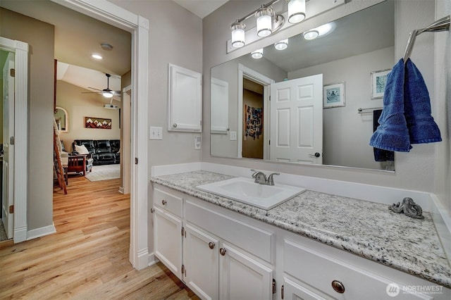 bathroom with ceiling fan, wood finished floors, vanity, and baseboards