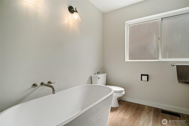 12062 Neppel Rd, Moses Lake, WA 98837 - bathroom with a freestanding tub, toilet, wood finished floors, and baseboards