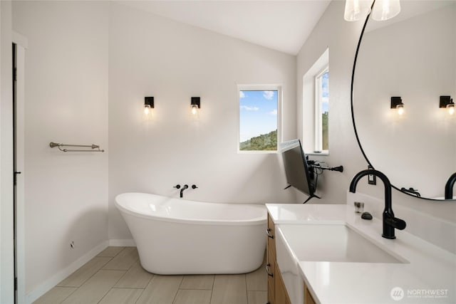 12062 Neppel Rd, Moses Lake, WA 98837 - bathroom with vanity, lofted ceiling, a freestanding tub, tile patterned floors, and baseboards