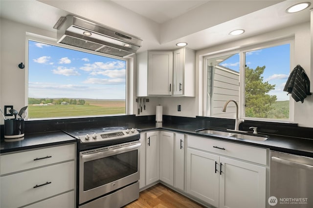 12062 Neppel Rd, Moses Lake, WA 98837 - kitchen with stainless steel appliances, a sink, dark countertops, range hood, and recessed lighting
