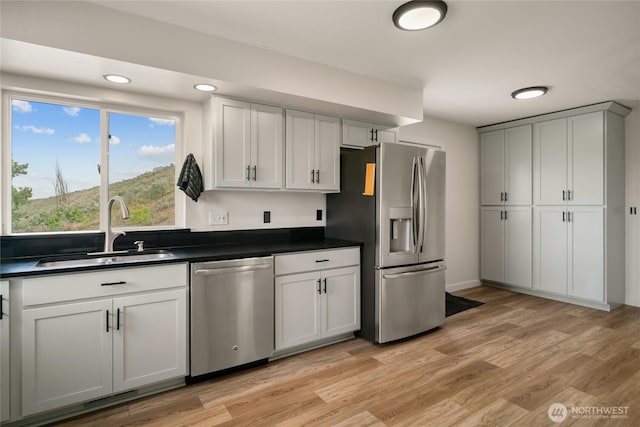 12062 Neppel Rd, Moses Lake, WA 98837 - kitchen featuring appliances with stainless steel finishes, a sink, dark countertops, light wood finished floors, and recessed lighting