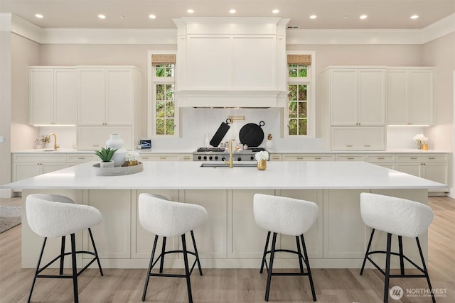 4207 Holly Ln, Mercer Island, WA 98040 - kitchen with healthy amount of natural light, a spacious island, light wood-style floors, white cabinets, and ornamental molding