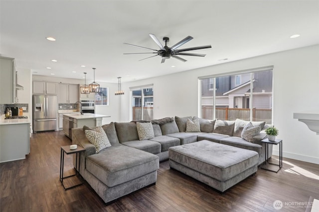 living room featuring ceiling fan, dark wood finished floors, recessed lighting, and a chandelier
