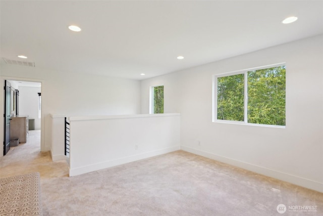 spare room featuring recessed lighting, light carpet, and baseboards
