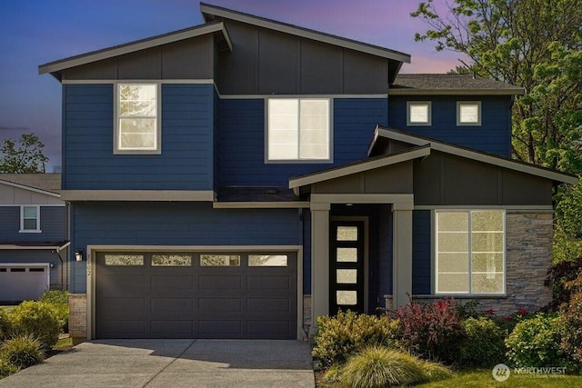 contemporary house with an attached garage, concrete driveway, and stone siding